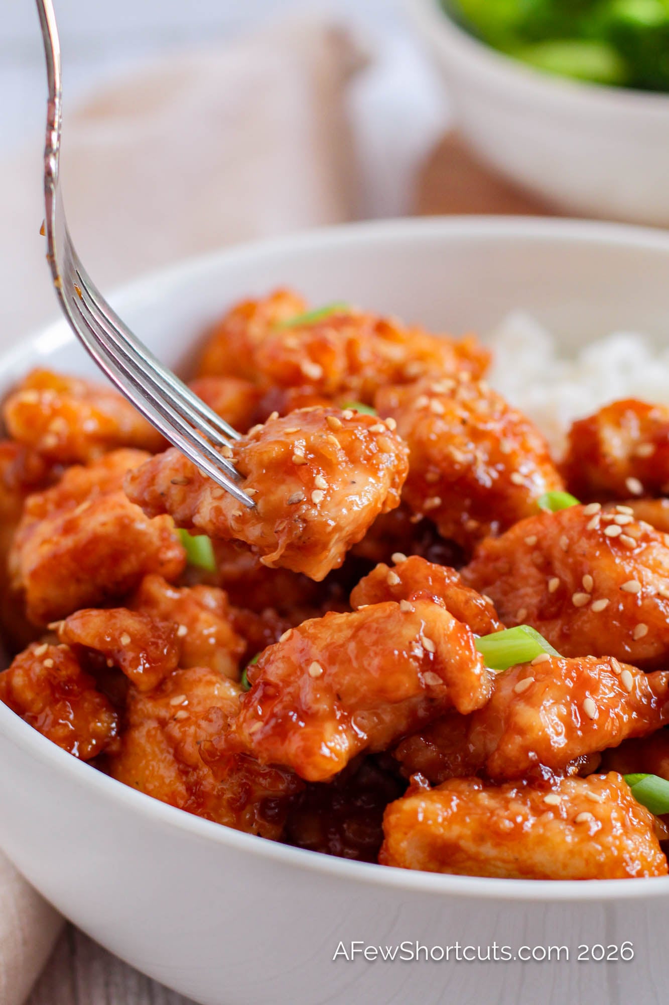 sticky sesame chicken in bowl with fork